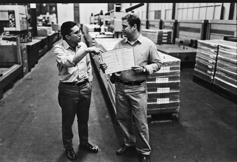 An advisor and plant manager standing on the production floor reviewing a checklist together