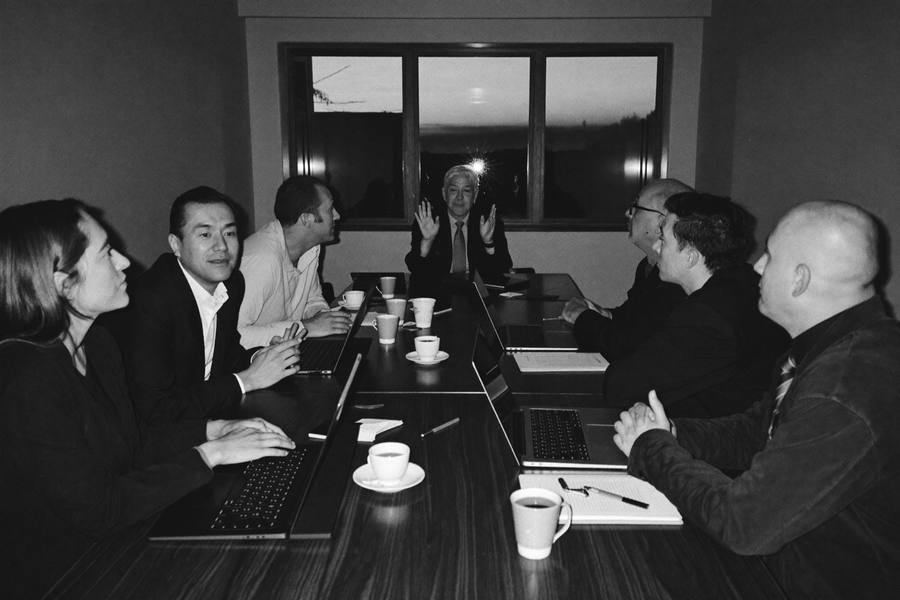 A monthly peer group of business owners in discussion around one conference table at dusk, no presenter