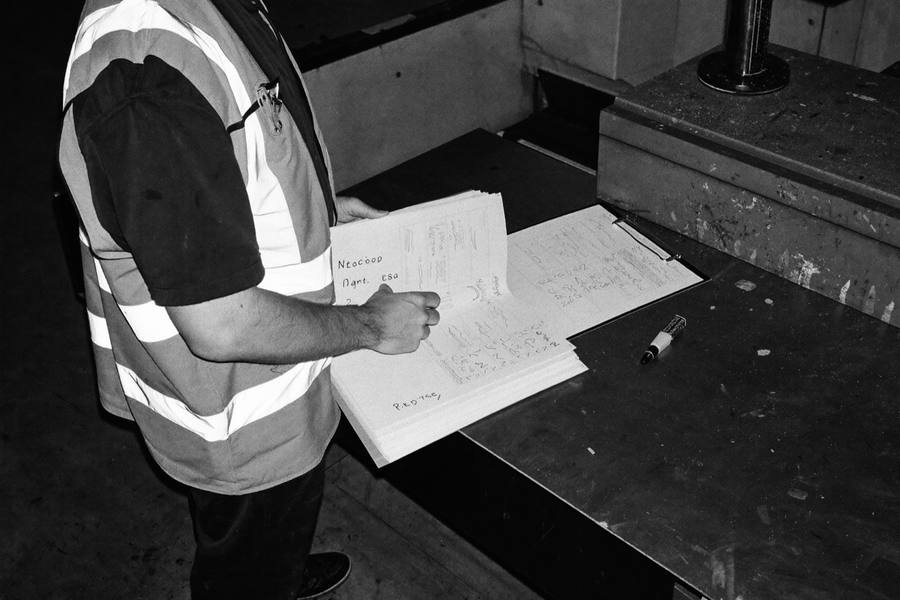A quality engineer working through a tabbed specification book beside a CNC machine